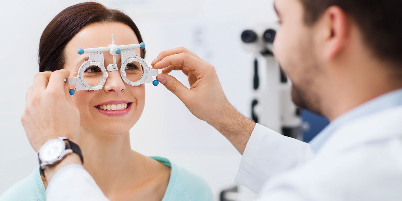 A smiling woman receives an eye exam