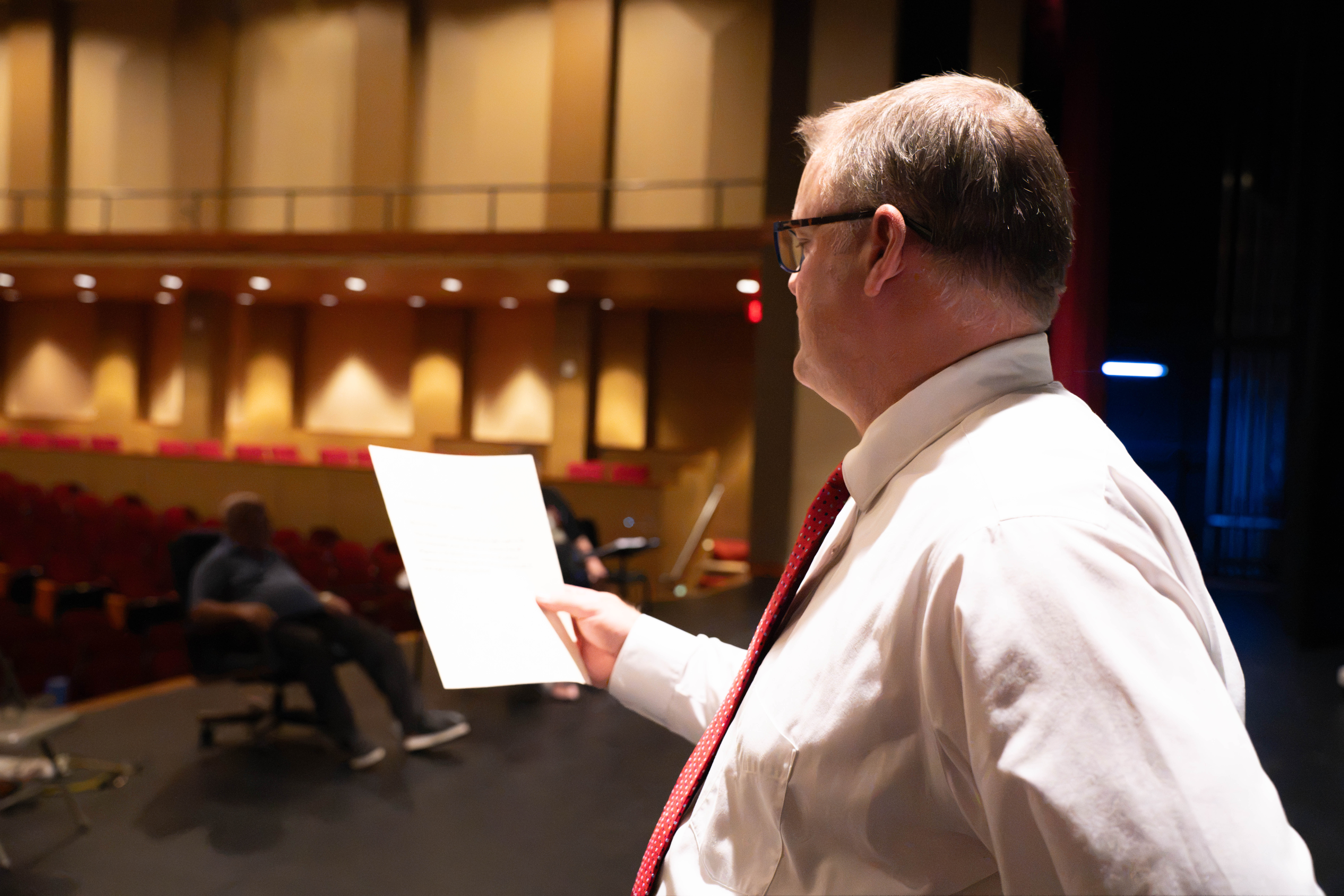 Atkin reading script on stage