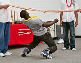 A male student bends backwards under a rope in a limbo game