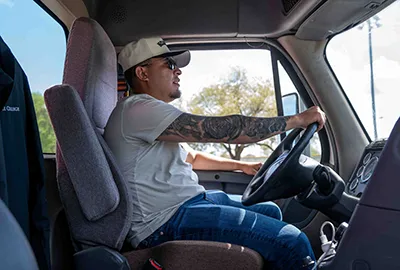 A man driving in the cabin of a truck