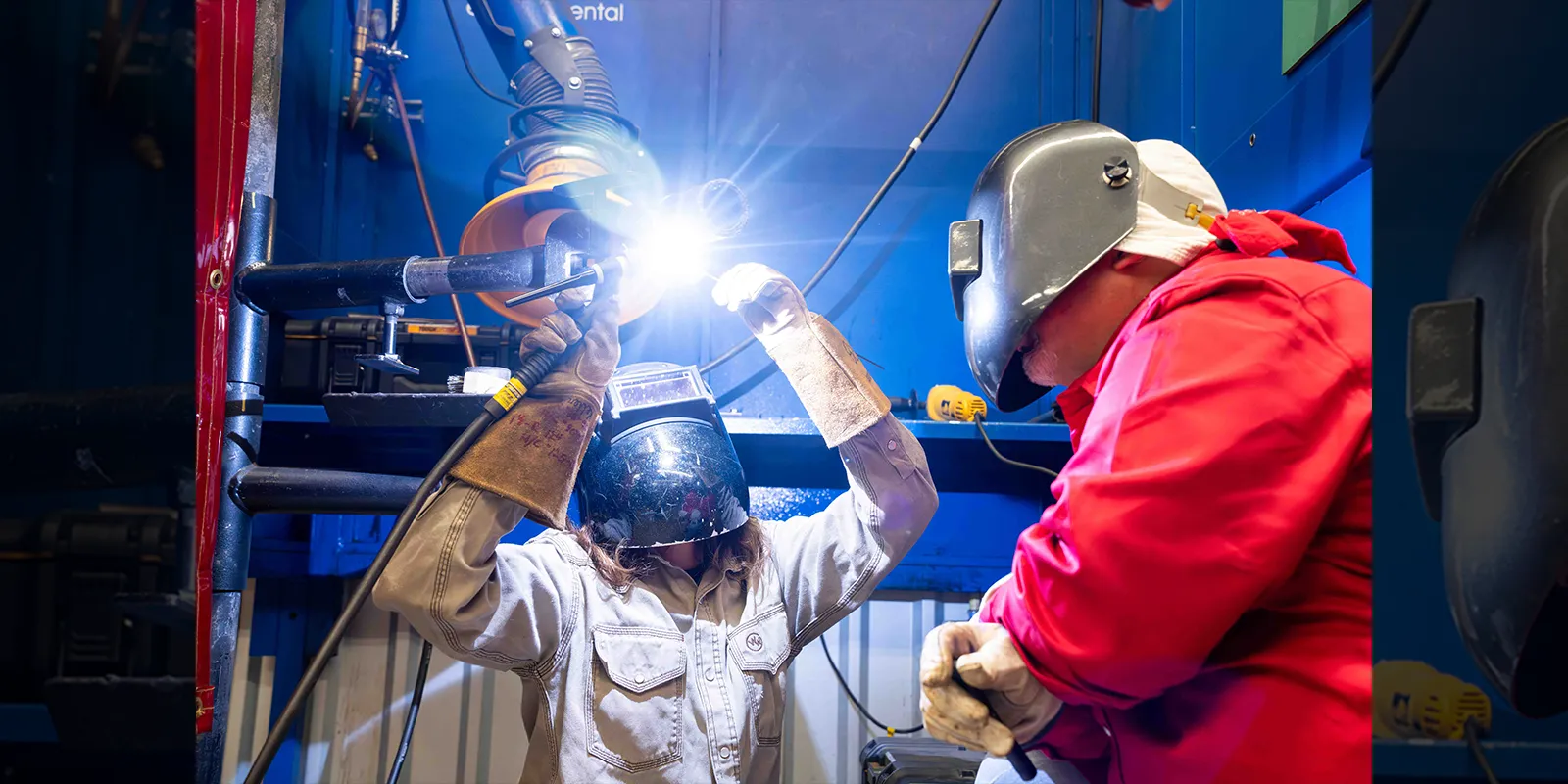 A welding student learns how to weld as an instructor looks on.