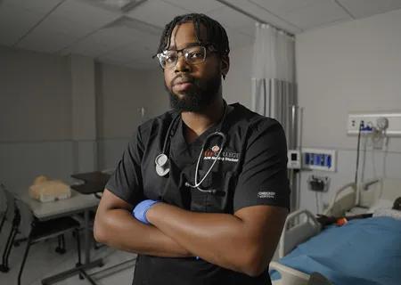 A male student with a stethescope, standing.