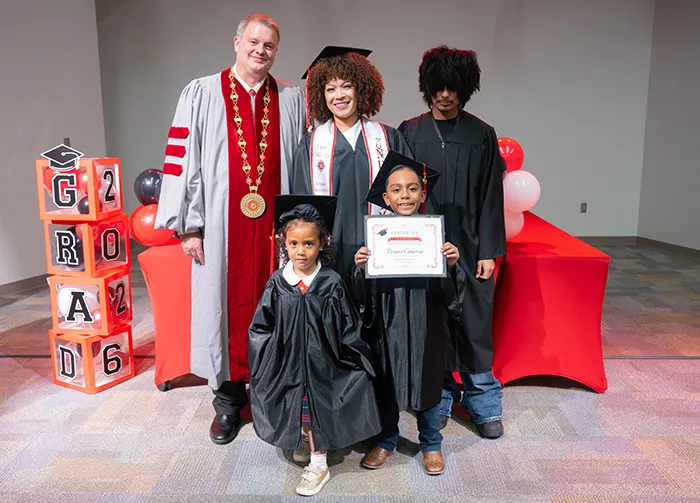 A graduating mother poses with her three children alongside Lee College President, Jacob Atkins